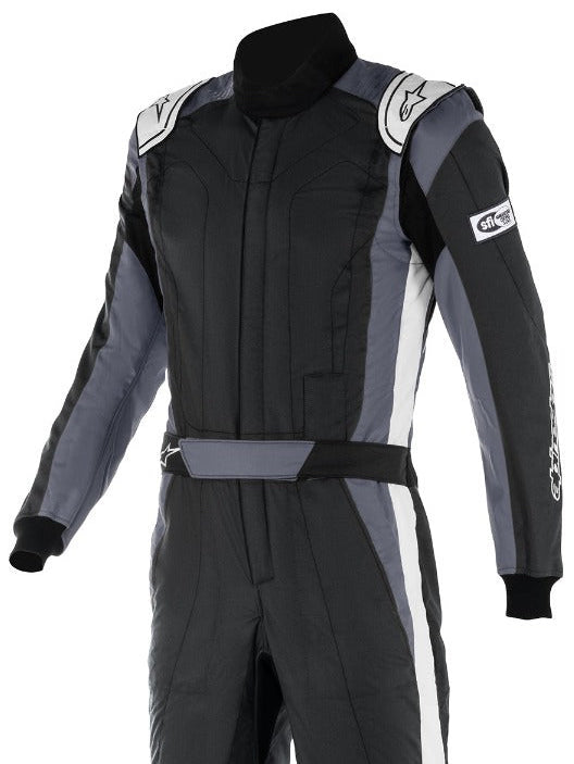Alpinestars GP Pro Comp v2 race suit, featuring a black and gray color scheme with sponsor logos, designed for auto racing with stretch panels and a tall ribbed collar.